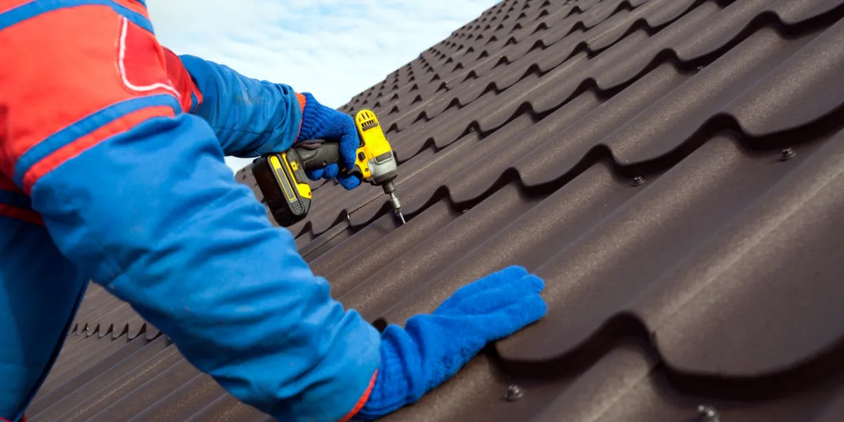 An image of a construction worker nailing a shingle to a roof.